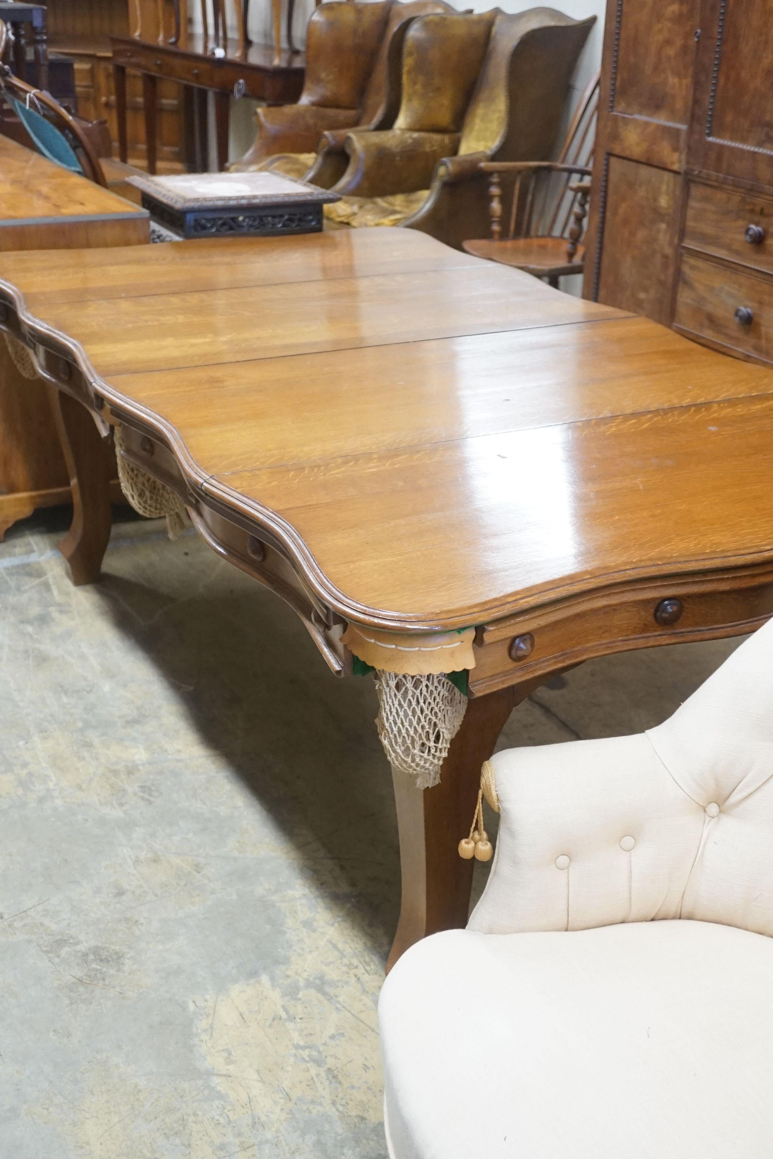 An early 20th century oak snooker / dining table, of rectangular serpentine form, with rise and fall action and full accessories, width 200cm depth 110cm height 74cm